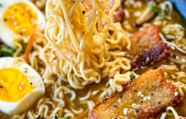 person holding chop sticks with pork belly ramen in a bowl