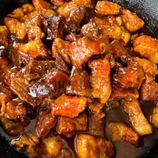 Traeger smoked pork belly burnt end with BBQ sauce in a cast iron skillet