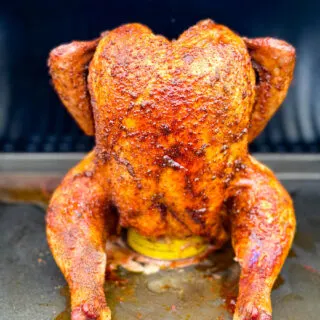 cooked, smoked seasoned whole chicken on a beer can in a Traeger smoker pellet grill