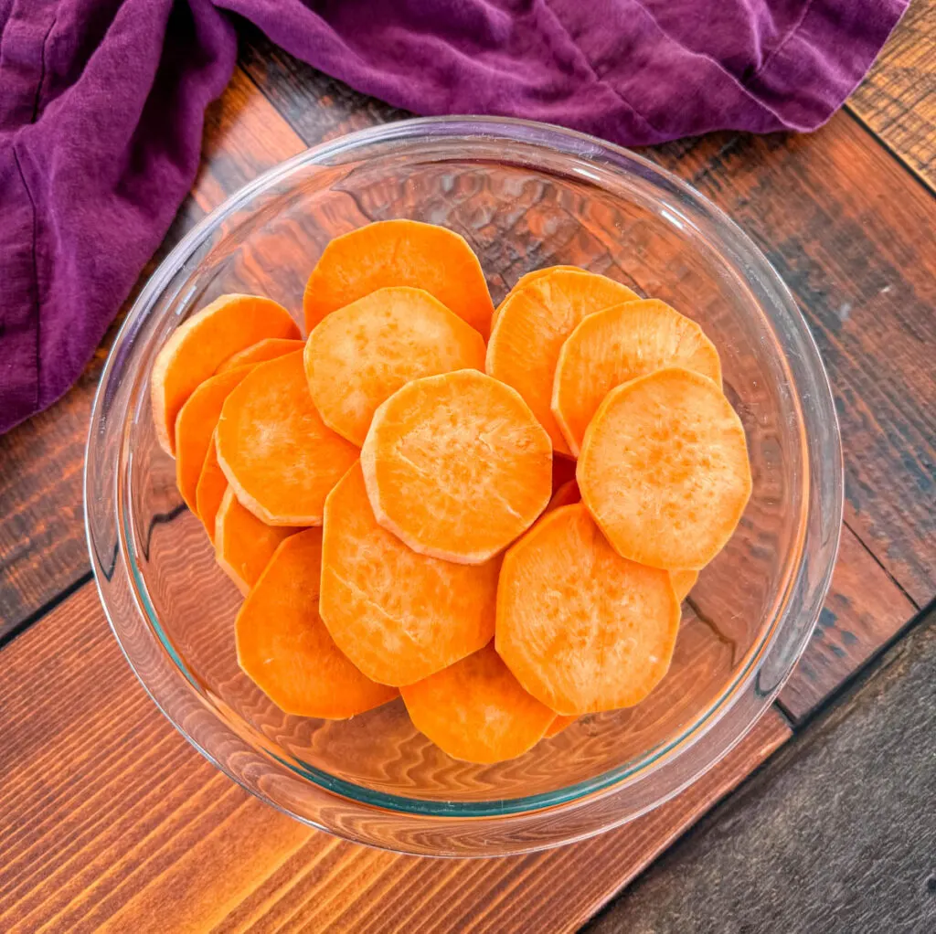 peeled and sliced sweet potato rounds in a glass bowl