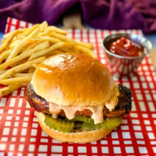 blackened chicken sandwich on a bun with spicy mayo on a plate with fries