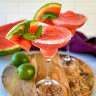 frozen margaritas in a sugar rimmed lined glass with fresh watermelon and limes