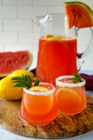 watermelon lemonade in glasses and a pitcher with fresh watermelon and lemons