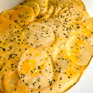 slow cooker cheesy potatoes in a white Crockpot with chives