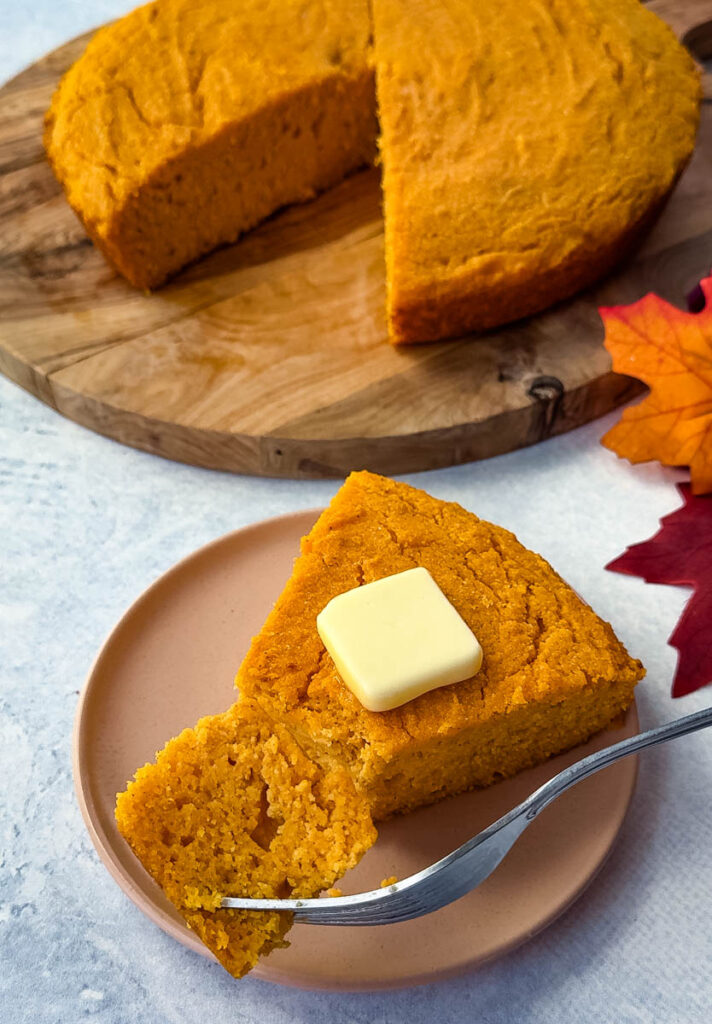 a slice of sweet potato cornbread with butter on a plate with a plate