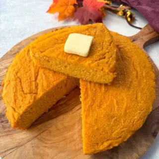 a slice of sweet potato cornbread with butter on top of a pan of sweet potato cornbread