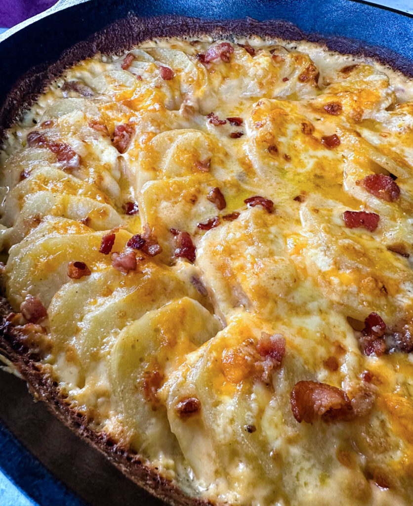 cheesy bacon potatoes au gratin in a cast iron skillet