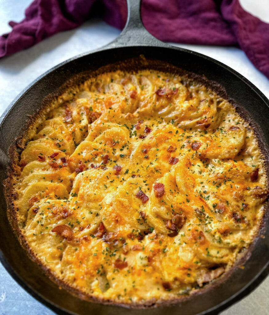 cheesy bacon potatoes au gratin in a cast iron skillet