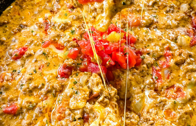 person holding chip with Rotel cheese dip with ground beef in a skillet