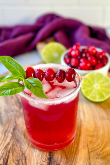 cranberry margarita with fresh cranberries and herbs in a glass