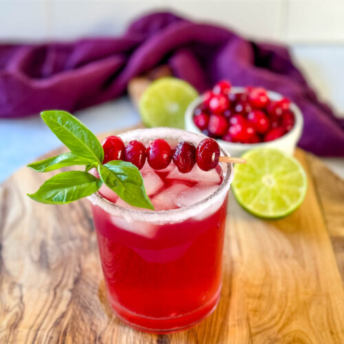 cranberry margarita with fresh cranberries and herbs in a glass