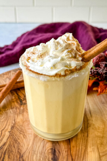 spiked eggnog with liquor, cinnamon, and whipped cream on a flat surface