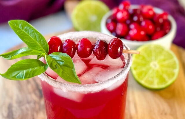 cranberry margarita with fresh cranberries and herbs in a glass