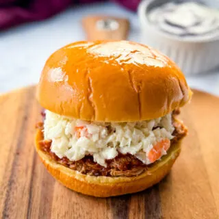 smoked pulled chicken sandwich with BBQ sauce and coleslaw on a plate