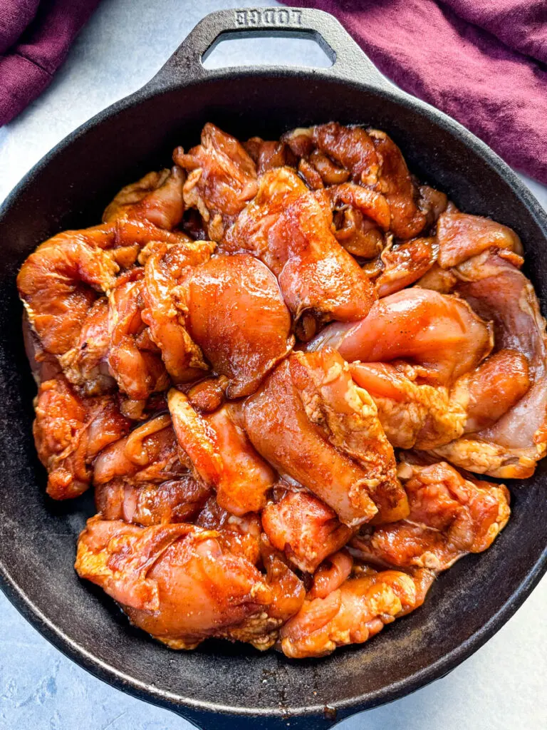 raw seasoned and marinated chicken thighs in a cast iron skillet