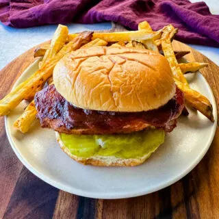 baked bbq chicken breast sandwich with fries on a platte