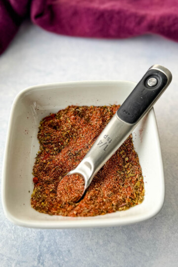 collard greens seasoning dry spices in a white bowl with a measuring spoon