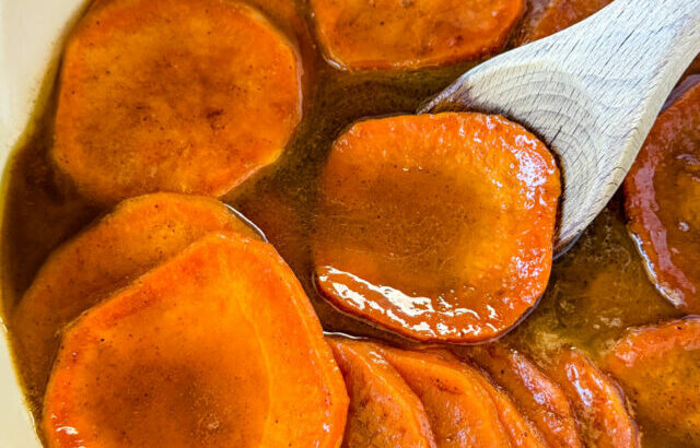 stovetop Southern soul food candied sweet potatoes yams in a Dutch oven with a wooden spoon