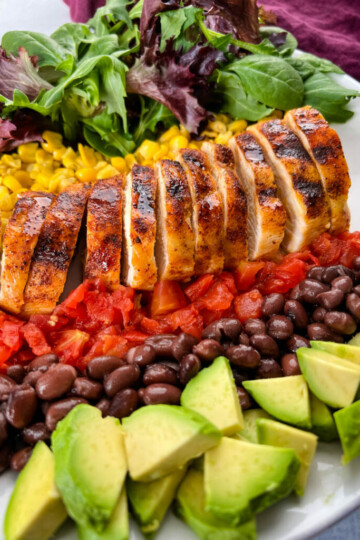 grilled chicken on a plate with vegetables and avocado