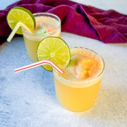 rainbow sherbet punch in a cup with a lime and straw