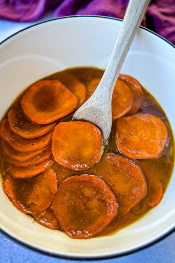 stovetop Southern soul food candied sweet potatoes yams in a Dutch oven with a wooden spoon