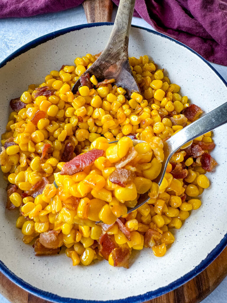 Southern fried corn with butter and bacon in a white bowl with a spoon
