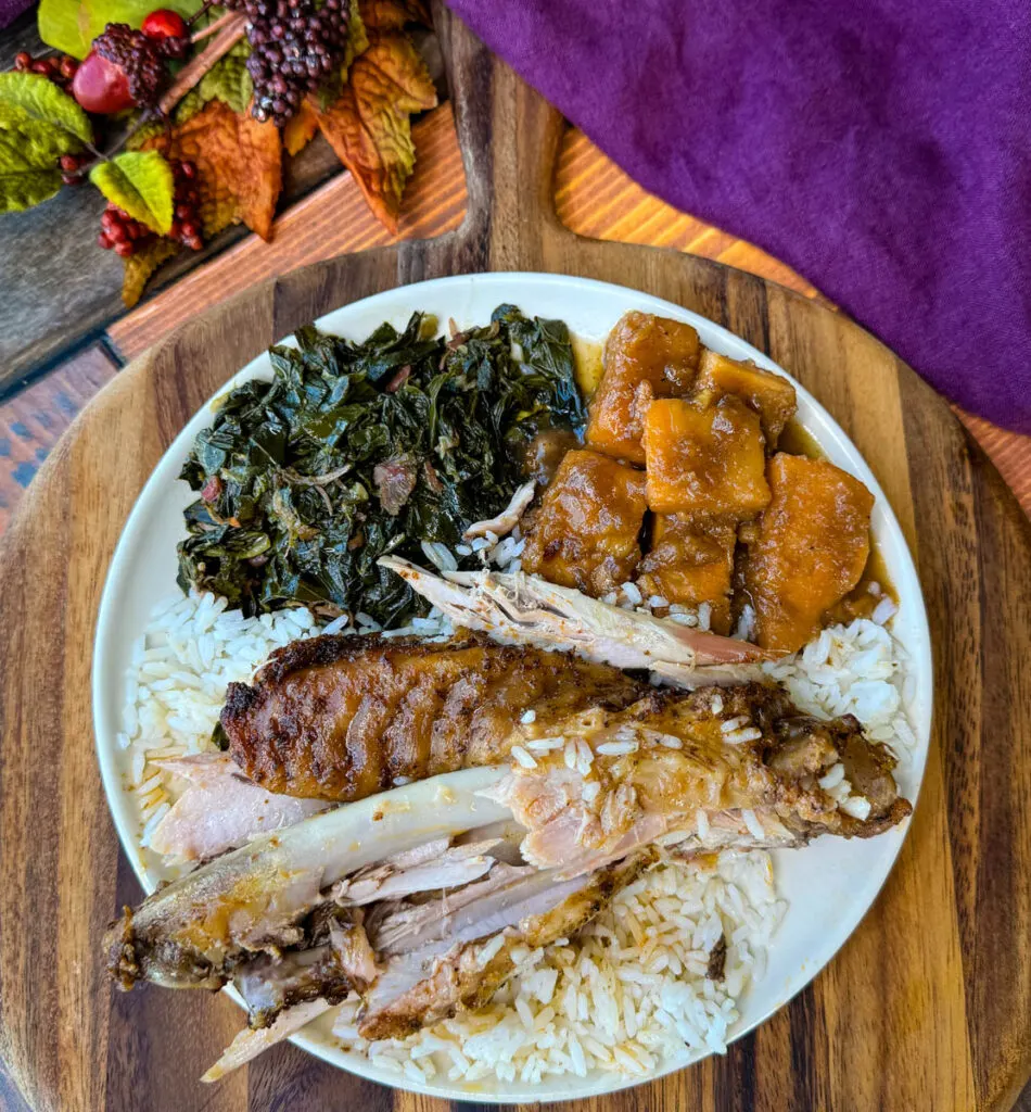 baked turkey wings falling off the bone on a plate with collard greens, sweet potatoes, and white rice