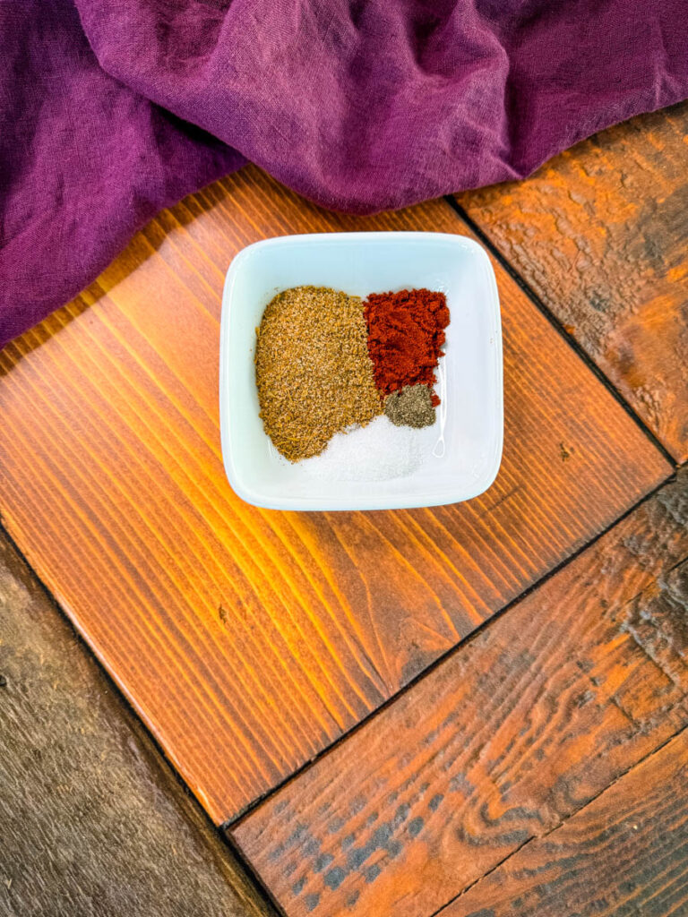 Creole seasoning, smoked paprika, salt, and pepper in a white bowl