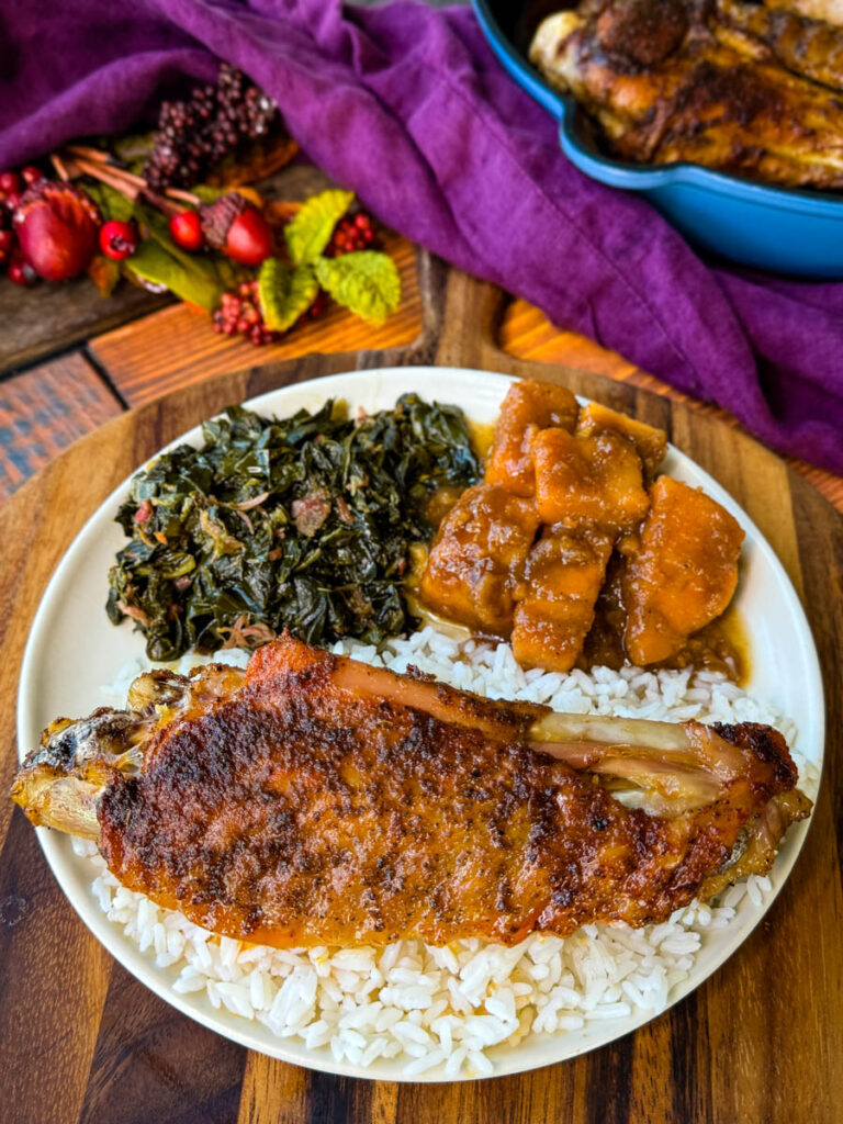 baked turkey wings on a plate with collard greens, sweet potatoes, and white rice