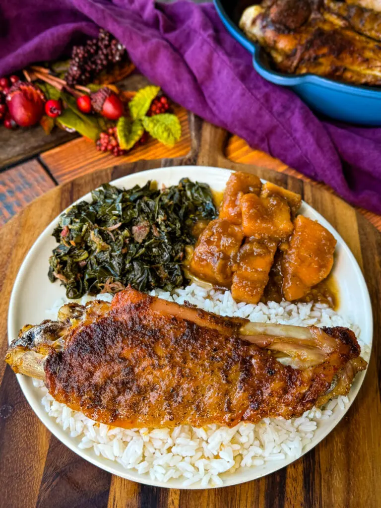 baked turkey wings on a plate with collard greens, sweet potatoes, and white rice