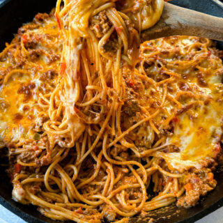 million dollar spaghetti in a cast iron skillet with a wooden spoon