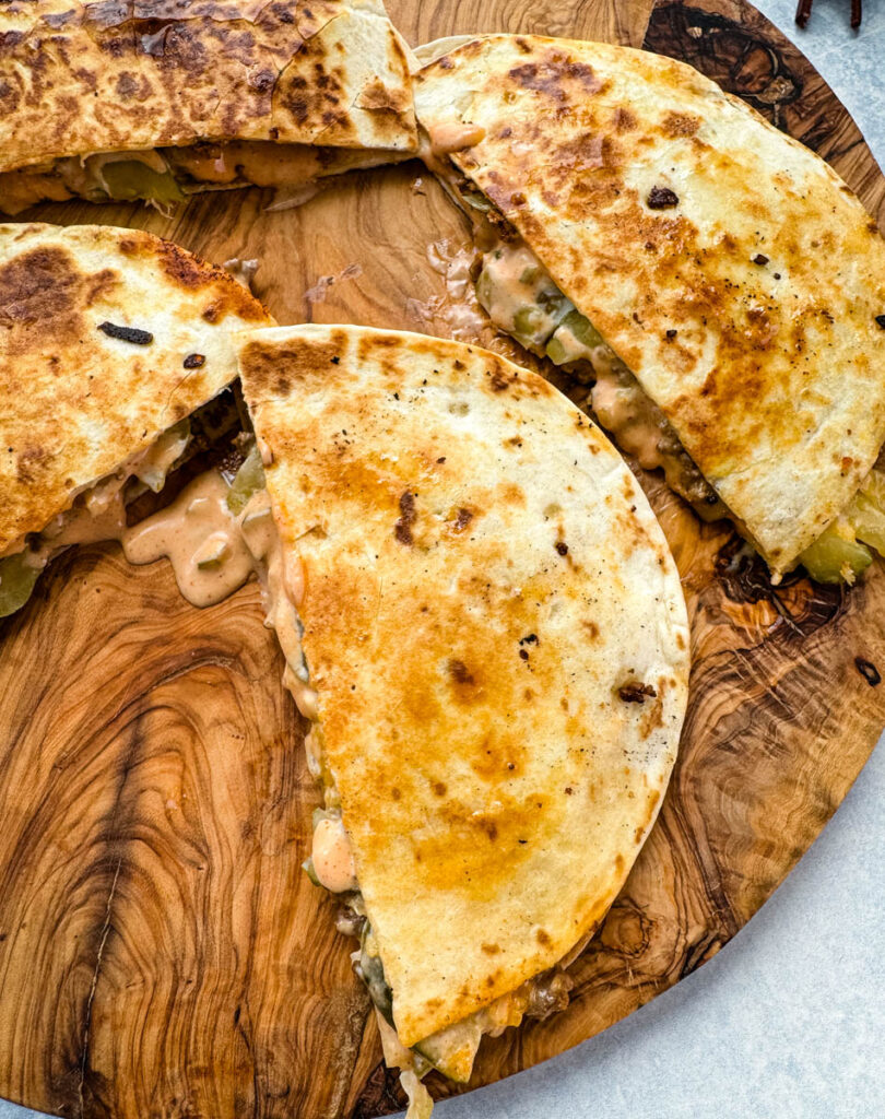 cheeseburger quesadilla with pickles and burger sauce on a wooden cutting board