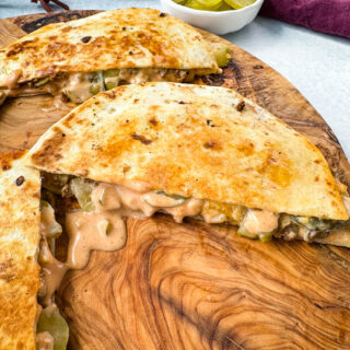 cheeseburger quesadilla with pickles and burger sauce on a wooden cutting board