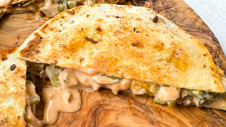 cheeseburger quesadilla with pickles and burger sauce on a wooden cutting board