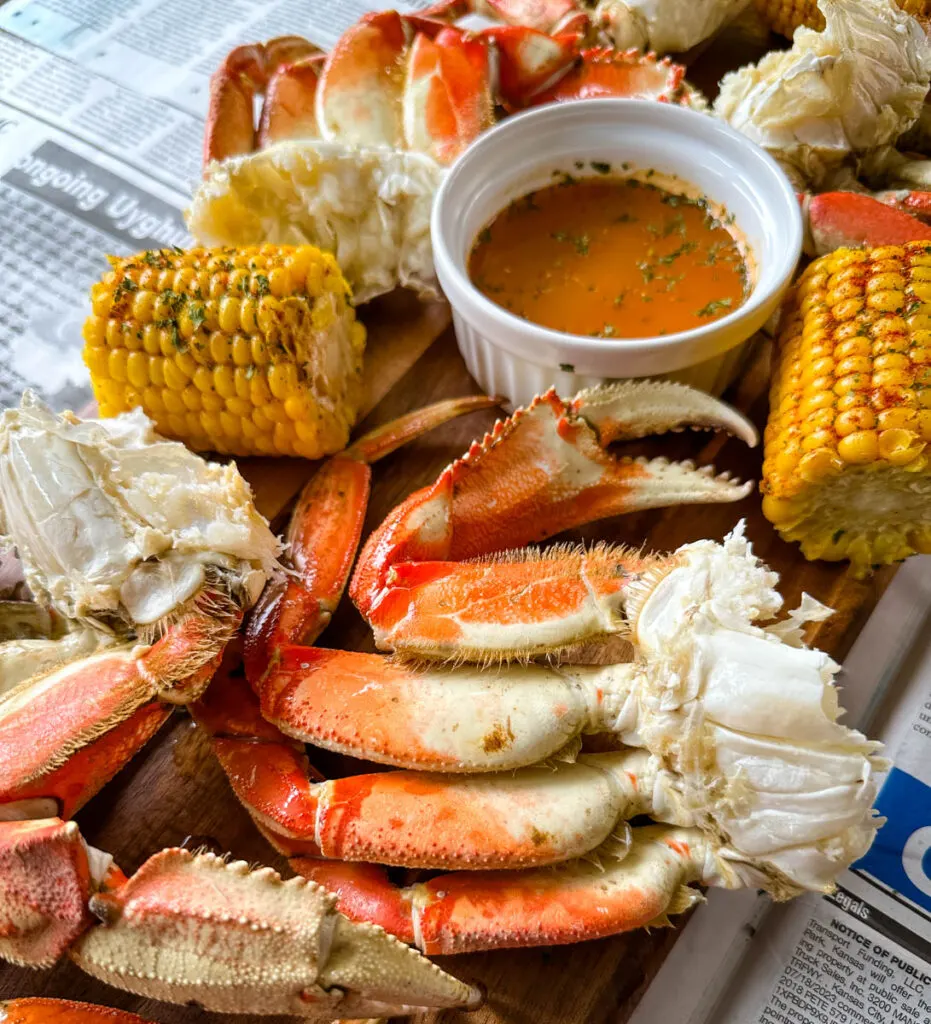 Dungeness crab legs on a platter with corn on the cob and lemon garlic butter sauce