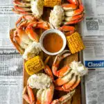 Dungeness crab legs on a platter with corn on the cob and lemon garlic butter sauce