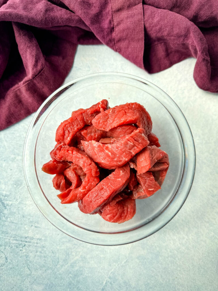 raw sliced flank steak i a glass bowl