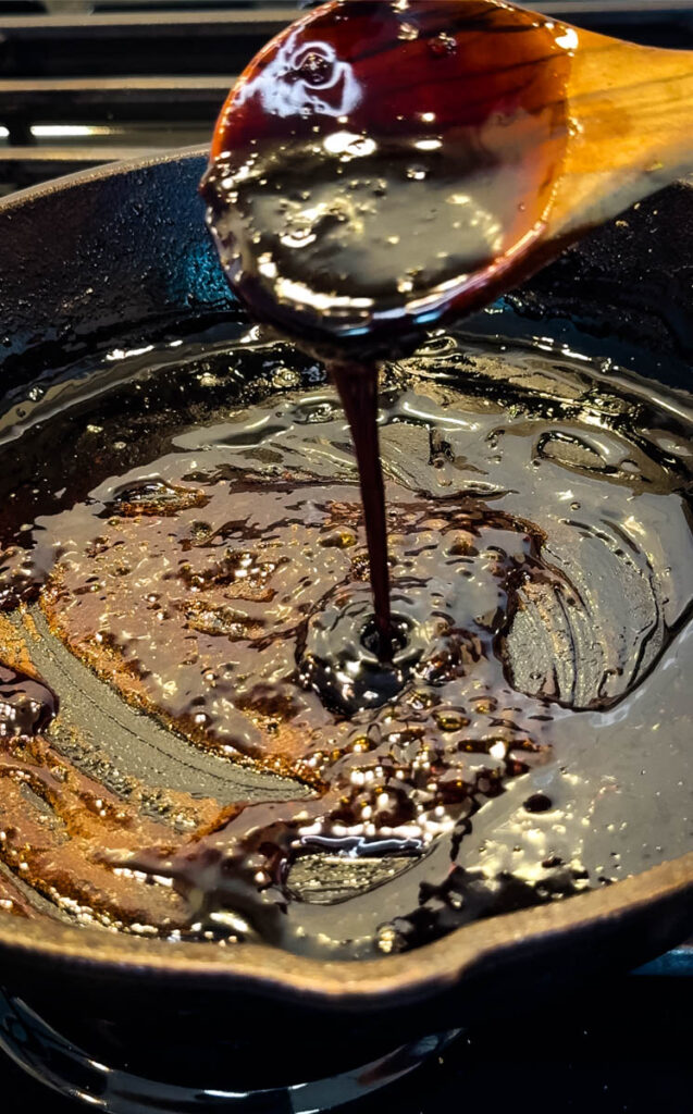 stir fry sauce in a wooden spoon an cast iron skillet