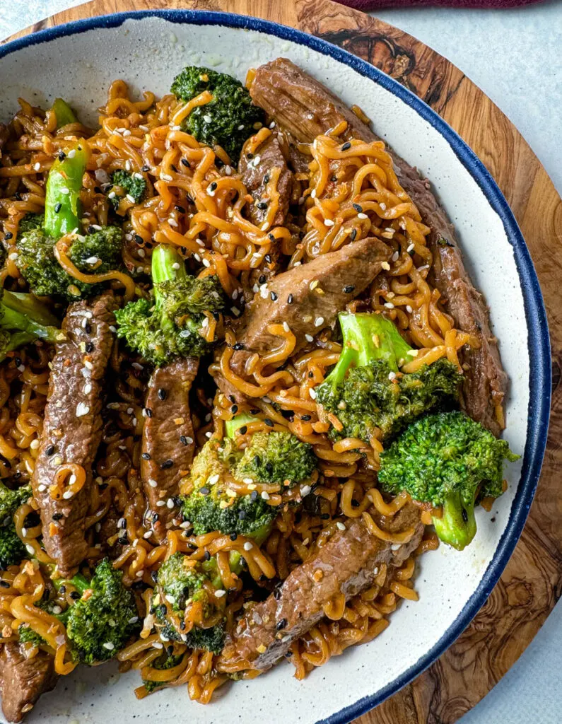 beef and broccoli stir fry with ramen noodles in a white bowl