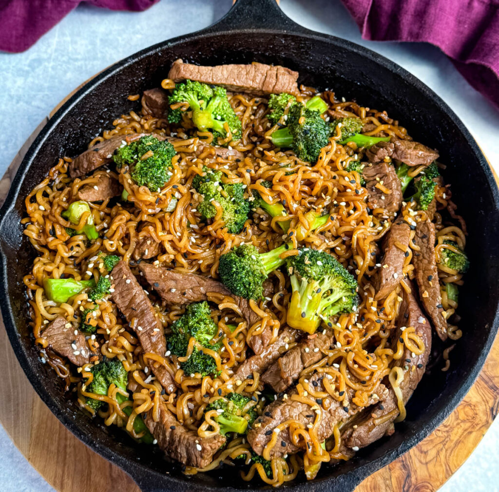 beef and broccoli stir fry with ramen noodles in a cast iron skillet