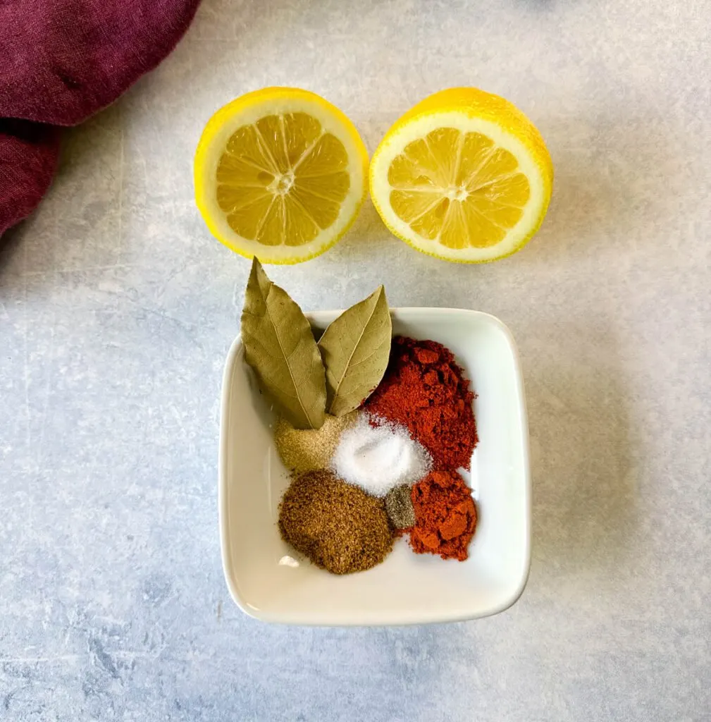 Cajun spices, bay leaves, and fresh lemon on a flat surface