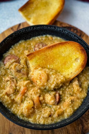 Cajun jambalaya soup in a black bowl with a piece of French bread