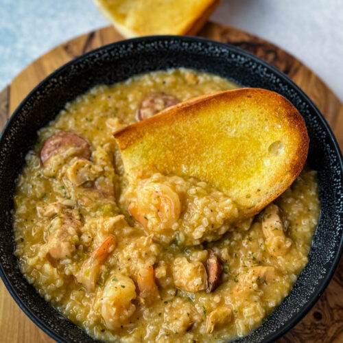 Cajun jambalaya soup in a black bowl with a piece of French bread