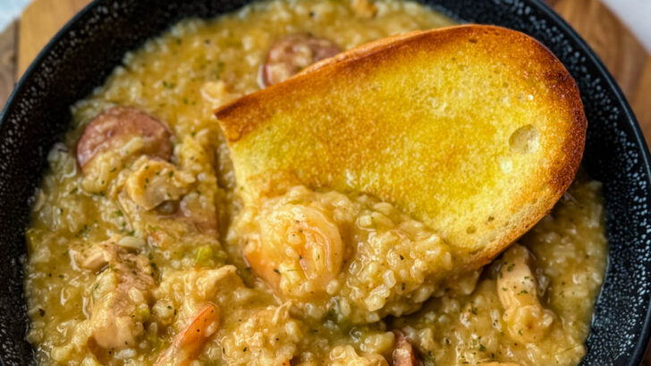 Cajun jambalaya soup in a black bowl with a piece of French bread