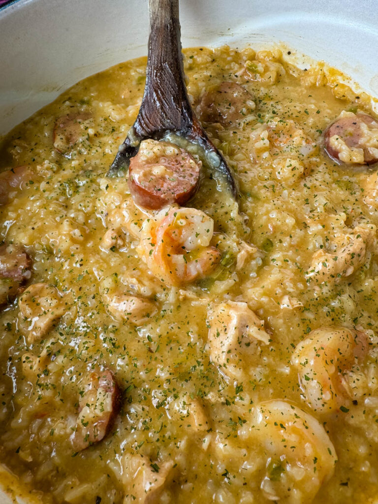 Cajun jambalaya soup in a Dutch oven with a wooden spoon