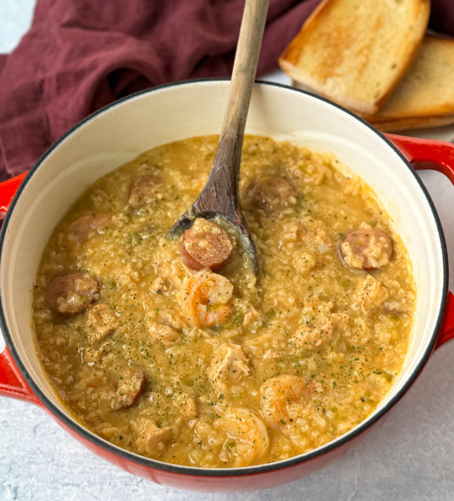 Cajun jambalaya soup in a Dutch oven with a wooden spoon