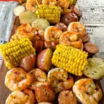 shrimp boil with andouille sausage, red potatoes, and corn on the cob on a flat surface with newspaper