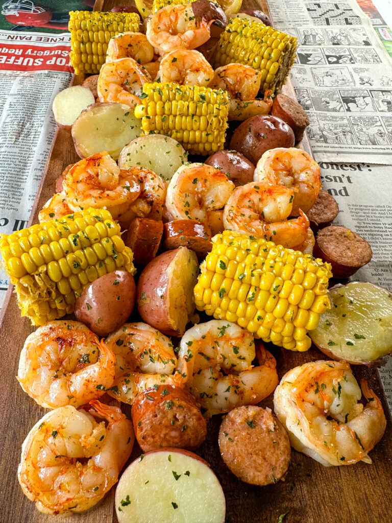 shrimp boil with andouille sausage, red potatoes, and corn on the cob on a flat surface with newspaper