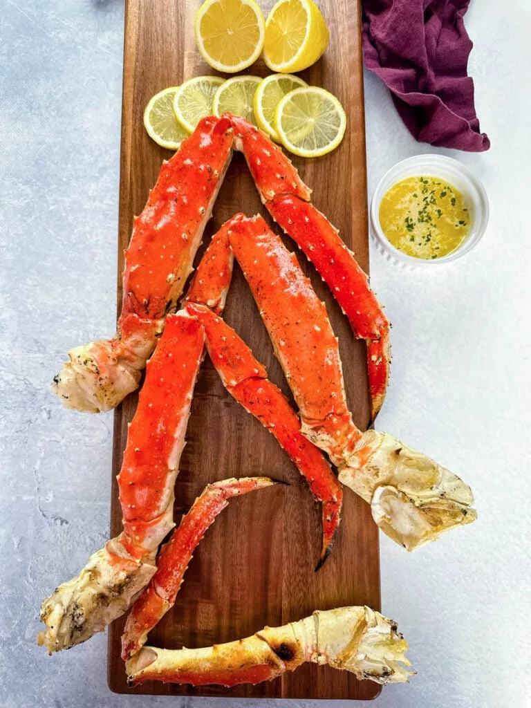 grilled crab legs on a wooden board with fresh lemon