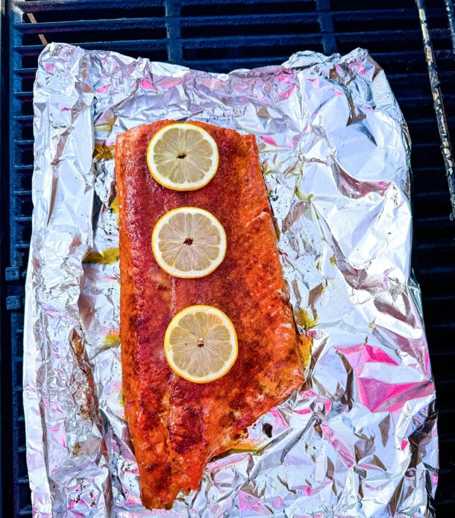 salmon in foil on a grill with fresh lemons